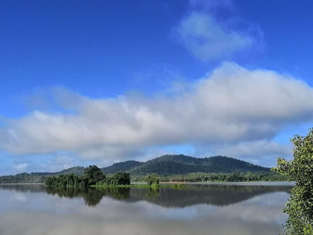 A sparkling lake reflecting thje white clouds and bright sky on a sunny morning with hills in the backdrop