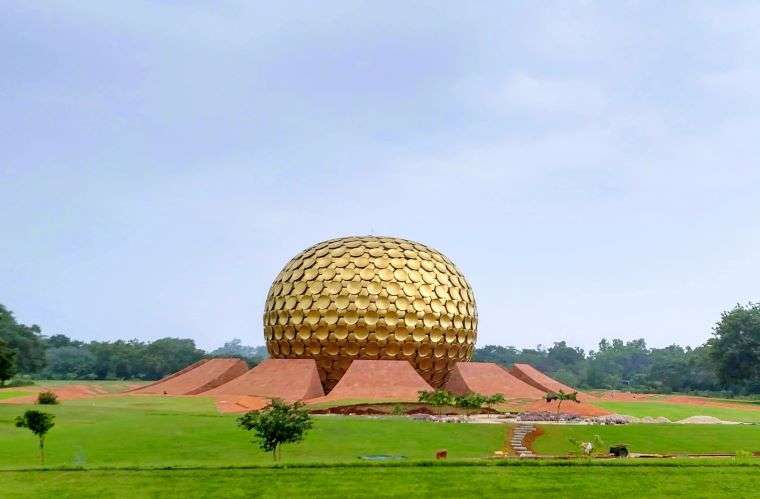 A golden sperical monument in a lush green park. This is Matrimandir - the meditation center of  Auroville