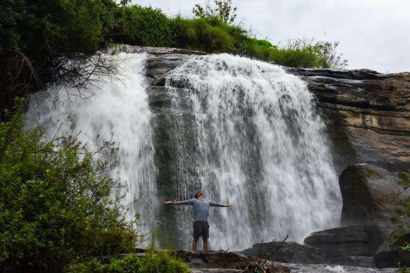 Majestic waterfalls anda man standing underneath