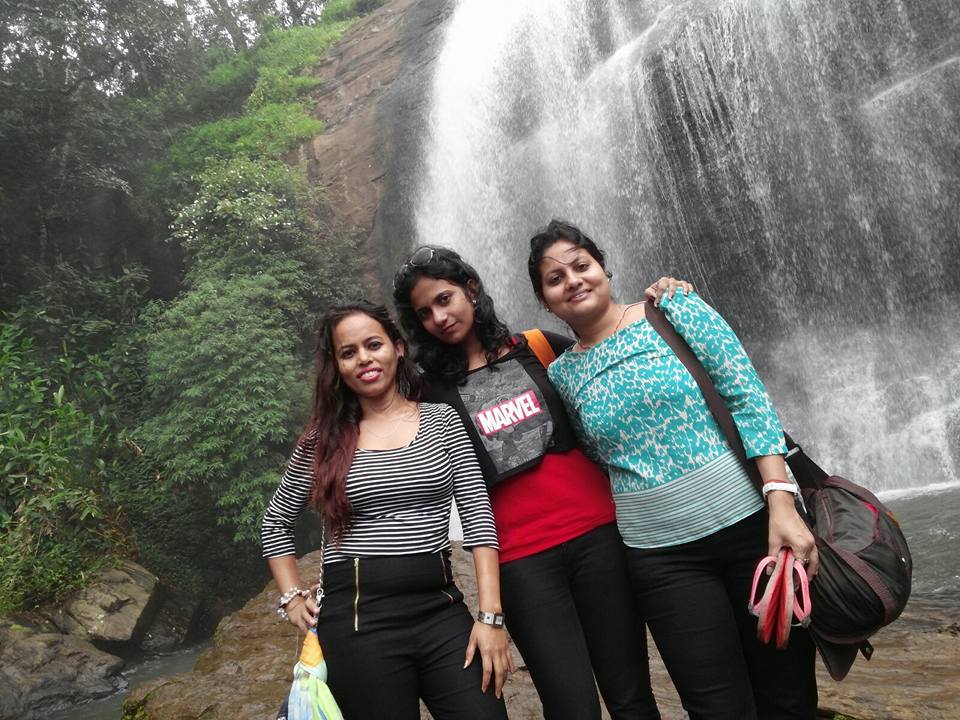 A group of three girls posing infront of the majestic Chelvara Falls pouring at its full force in the monsoon