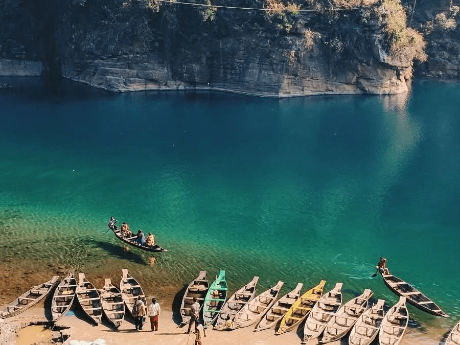 Top 10 Places to visit in India in Summer With Family in 2024 2 Sparkling clear lake reflecting emerald hues of the surrounding in Meghalaya with numerous colorful boats ready to sail